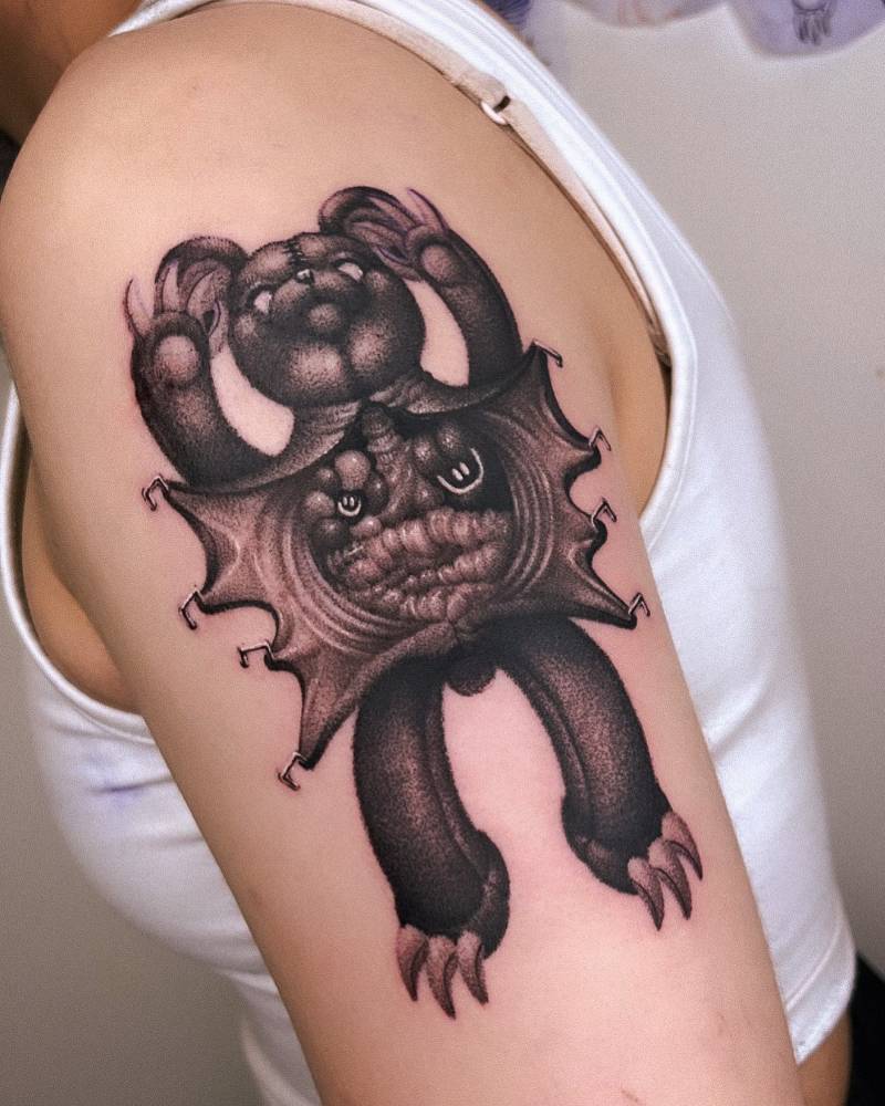 Teddy bear operation tattoo in dotwork style located on the upper arm.