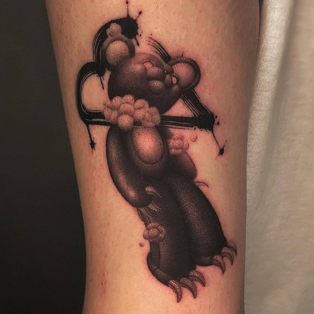 Cartoon style teddy bear tattoo located on the tricep.