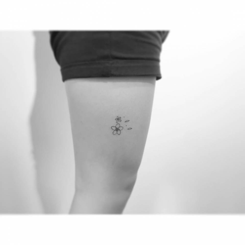 Minimalistic style flowers tattoo located on the thigh.