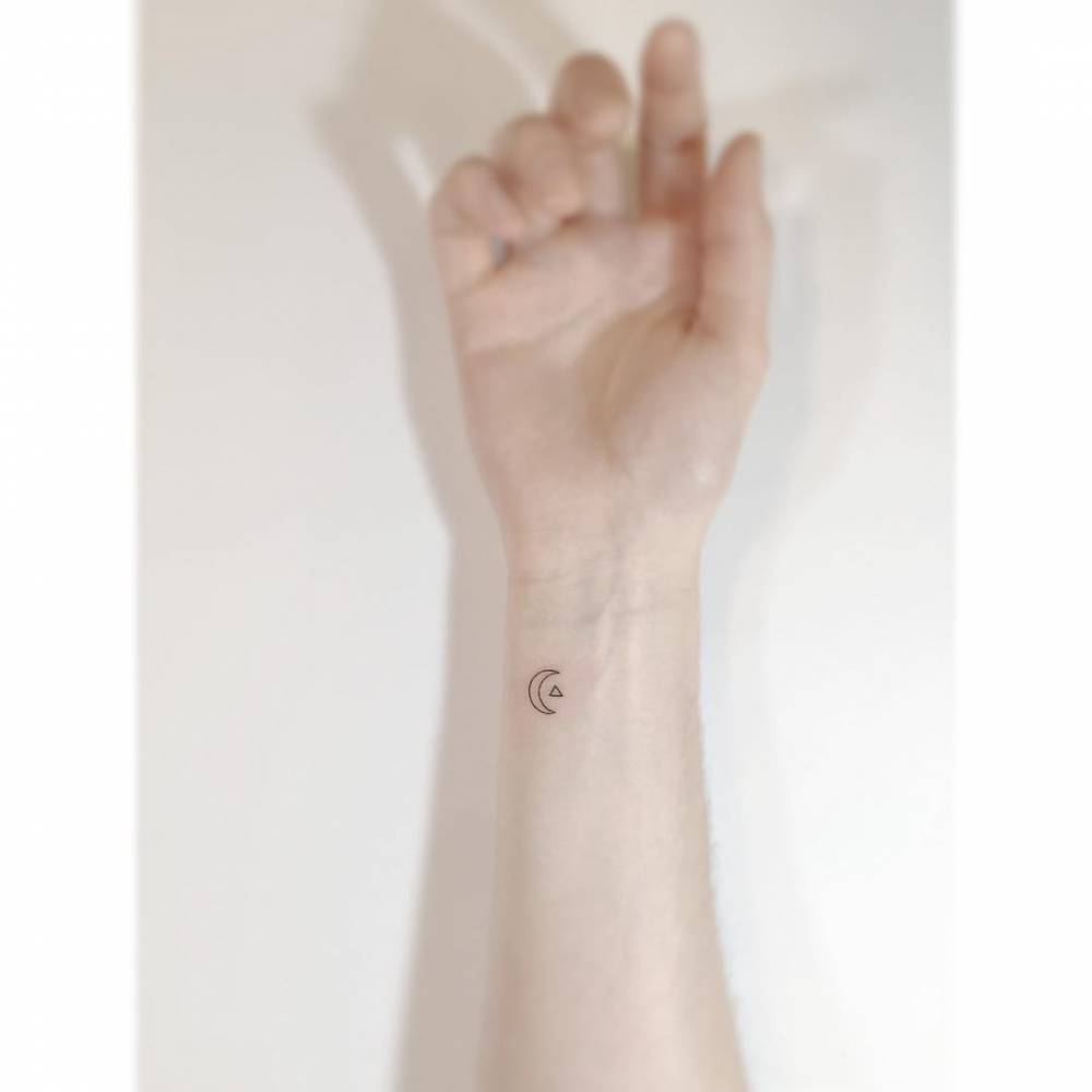 Tiny moon and triangle tattoo in minimalistic style placed on the wrist.