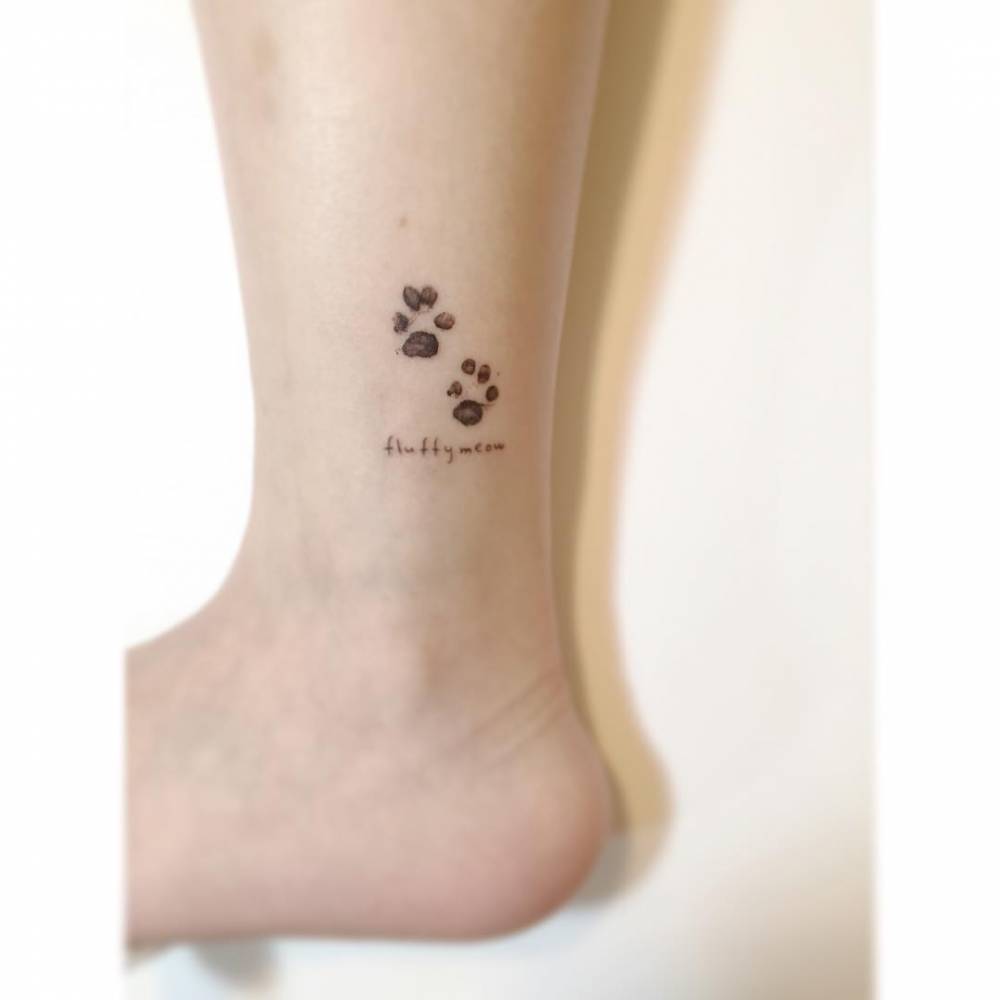 Dog paw prints tattoo in watercolor style located on the ankle.