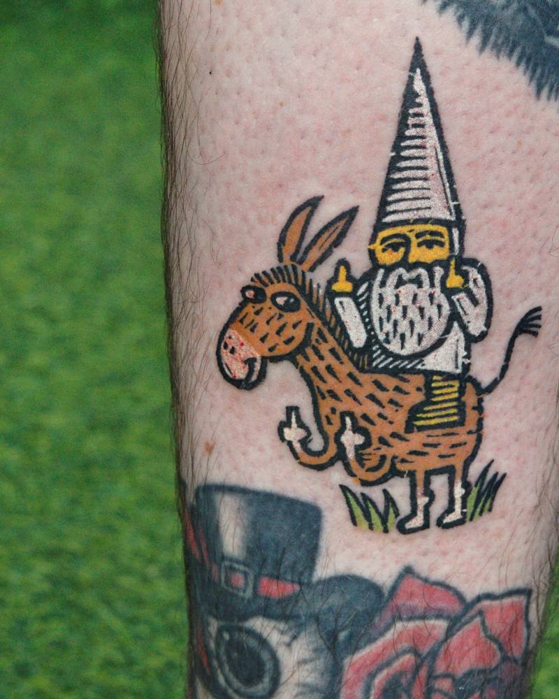 Gnome and donkey tattoo in pop art style located on the shin.