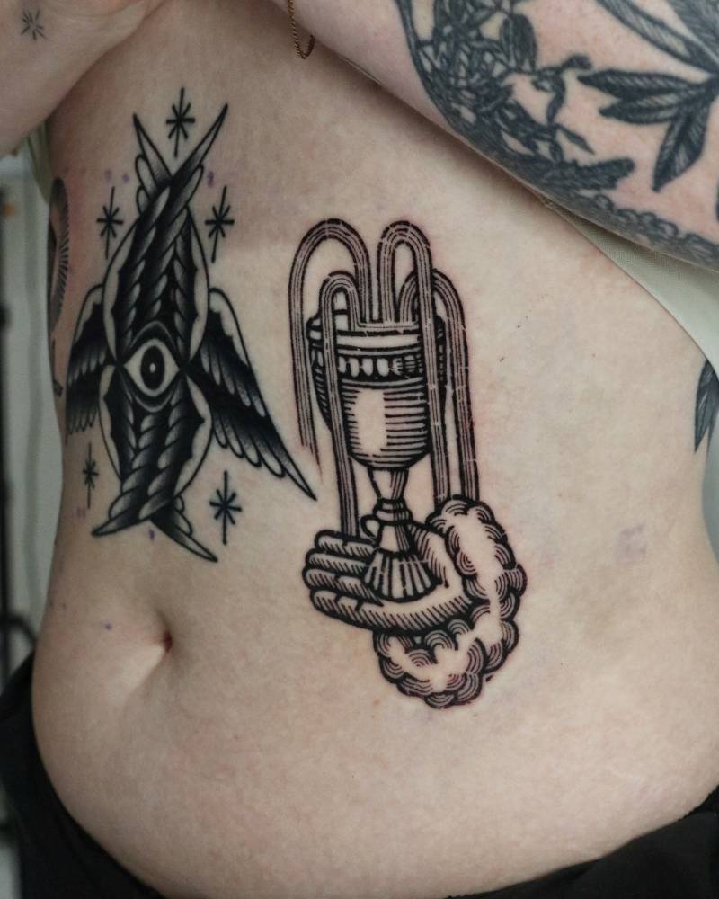Hand holding a chalice tattoo located on the rib, engraving style.