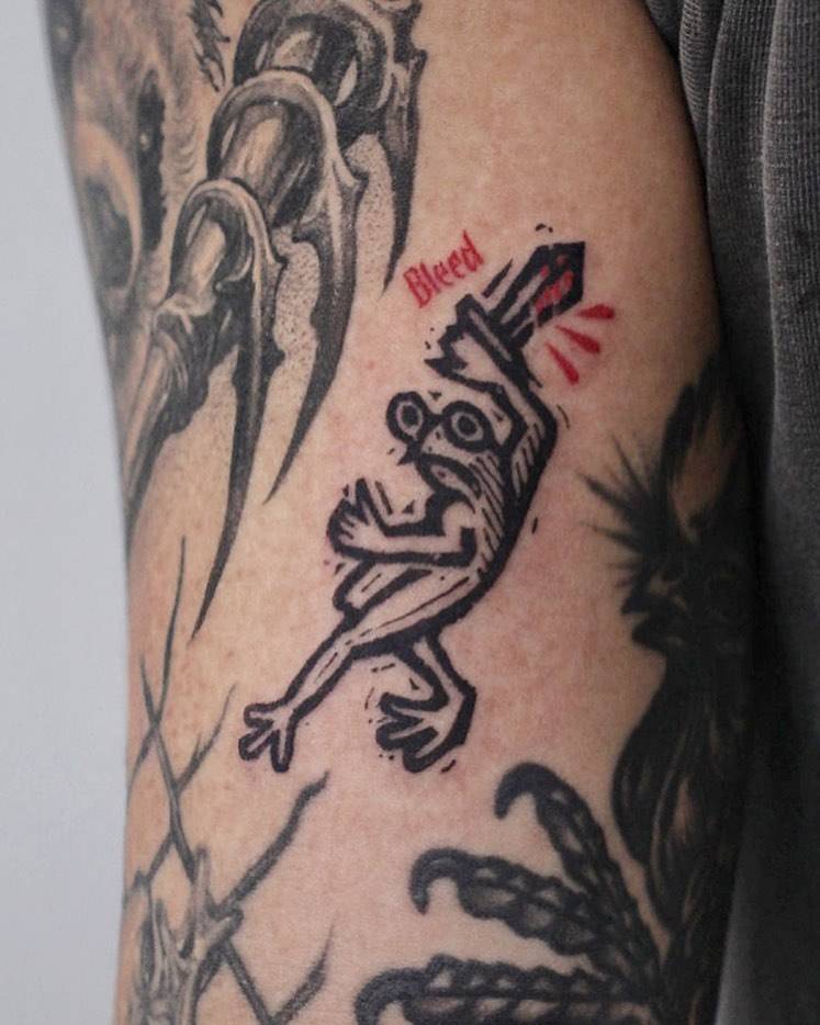 Assassin frog gap filler tattoo located on the tricep.