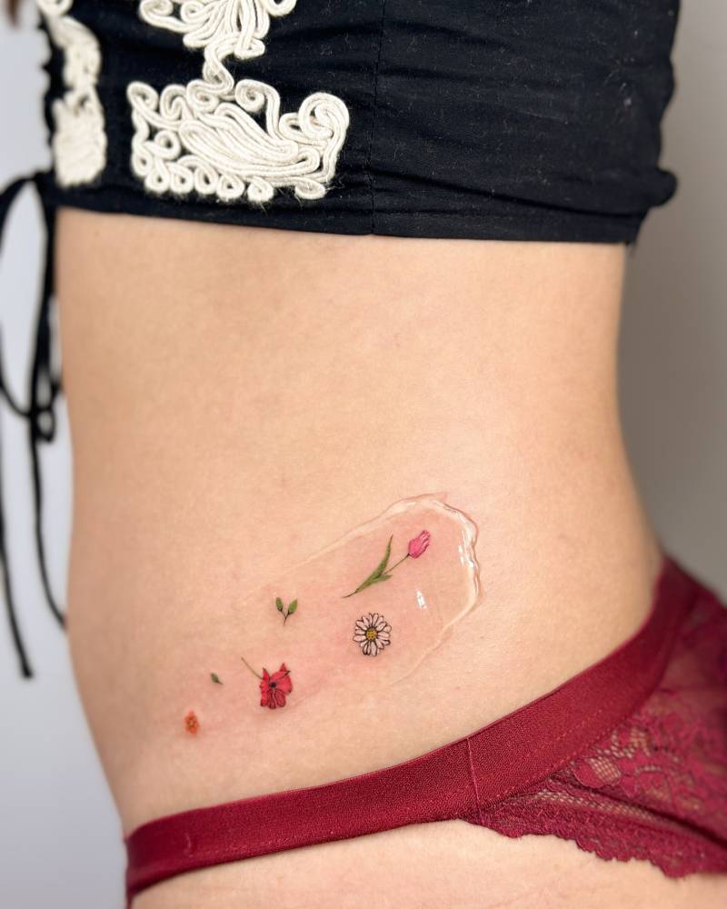 Tiny flowers tattoo in illustrative style placed on the waist.