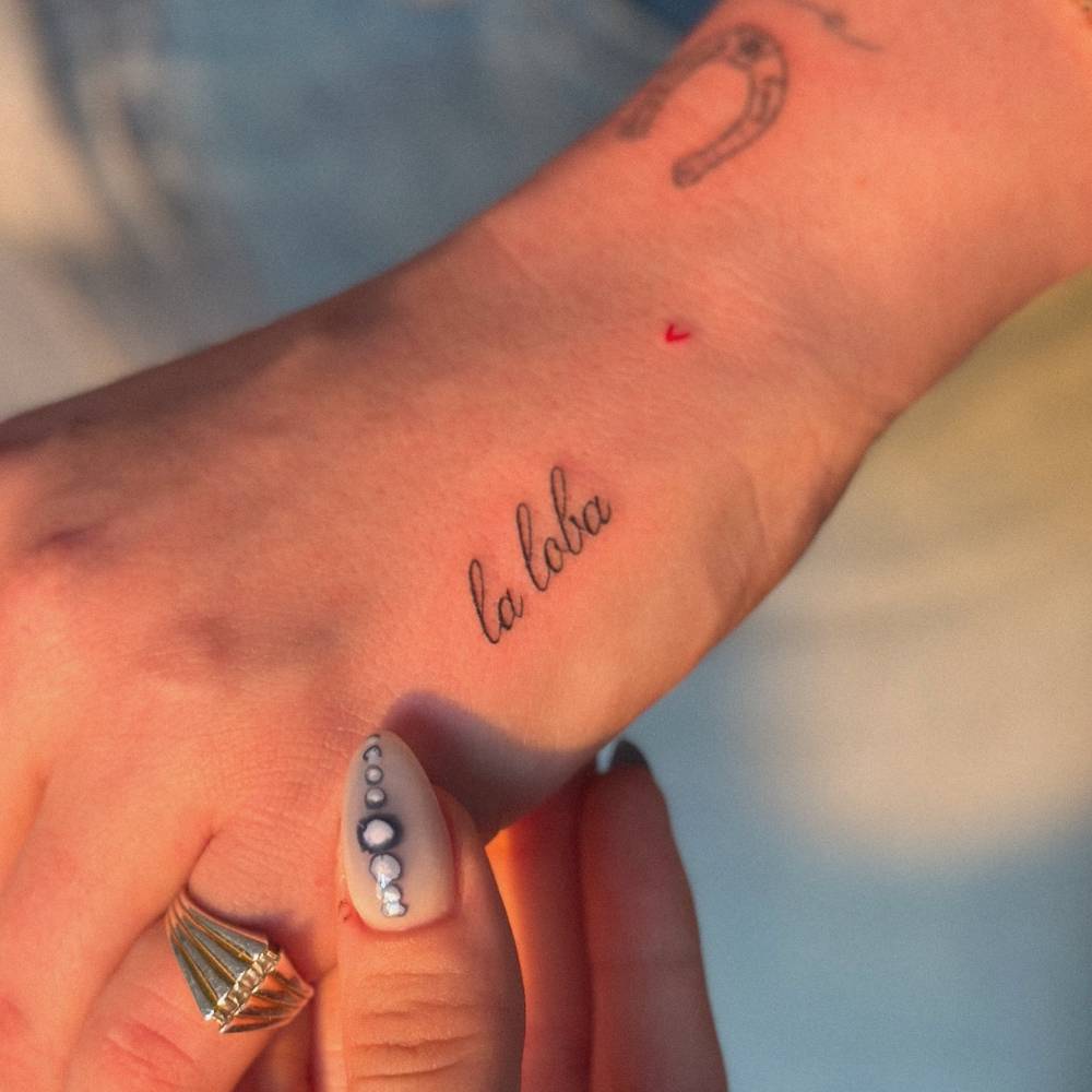 "La loba" lettering tattoo located on the hand.