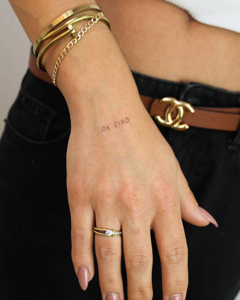 "Ok, ciao" lettering tattoo placed on the hand.