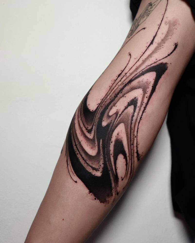 Abstract style tattoo in blackwork style located on the elbow.