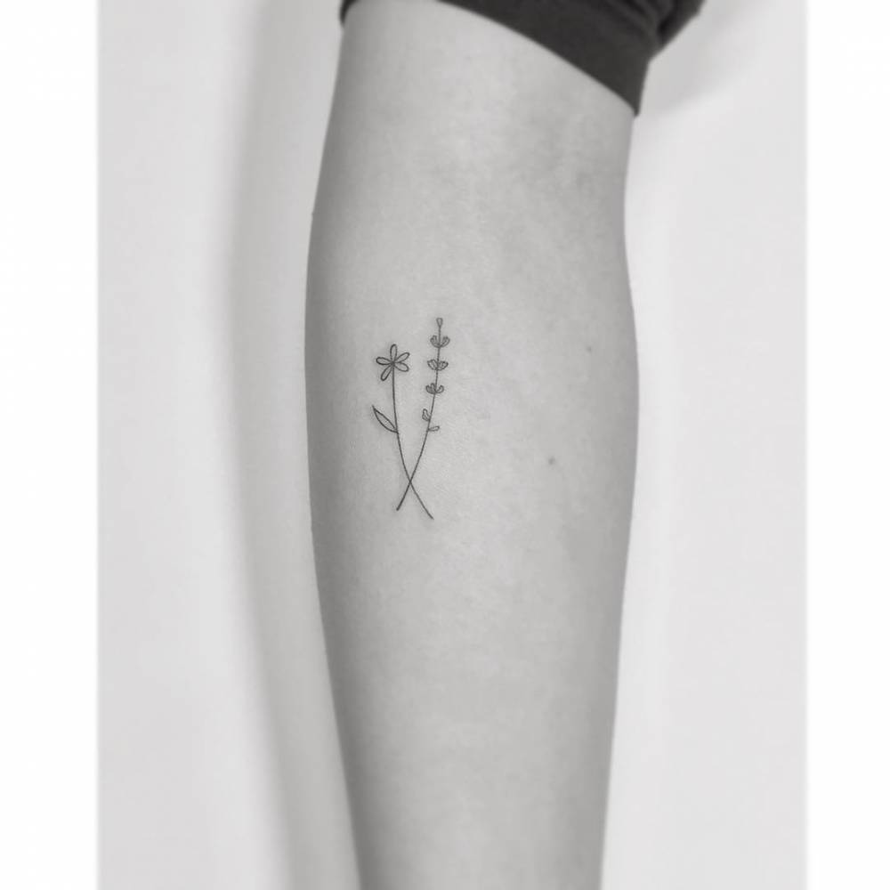 Daisy and lavender tattoo in minimalistic style placed on the inner forearm.