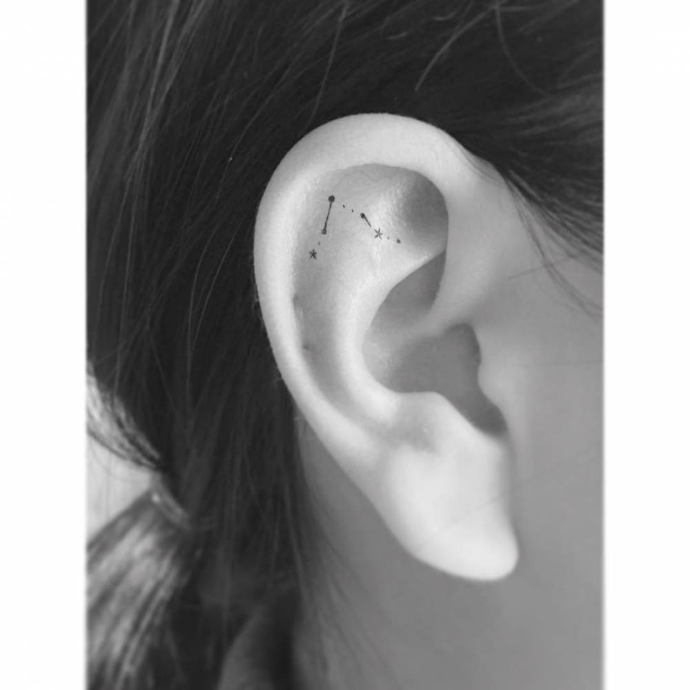 Tiny minimalistic Pisces constellation tattoo located on the ear.