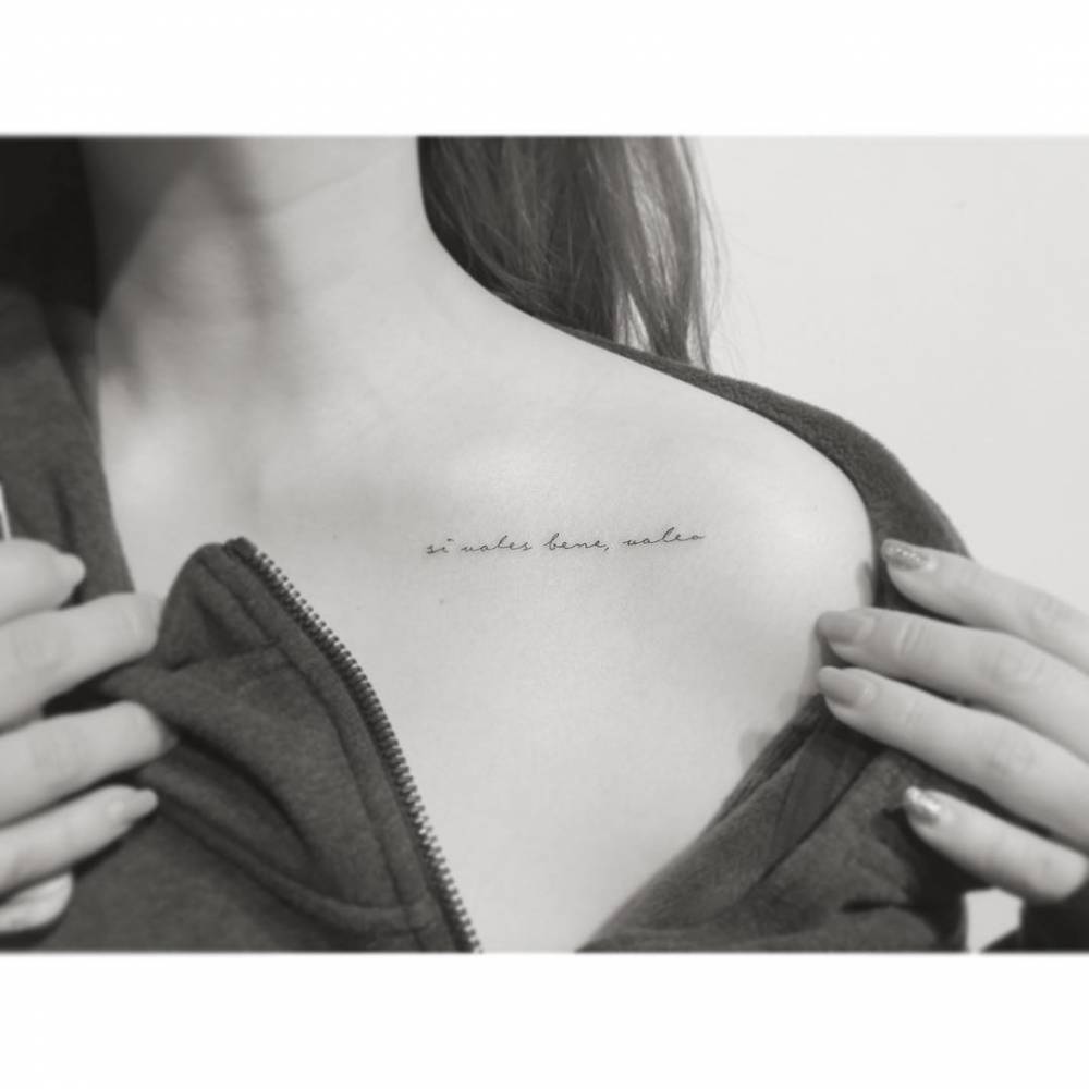 "Si vales bene, valeo" lettering tattoo handwritten on the collarbone.