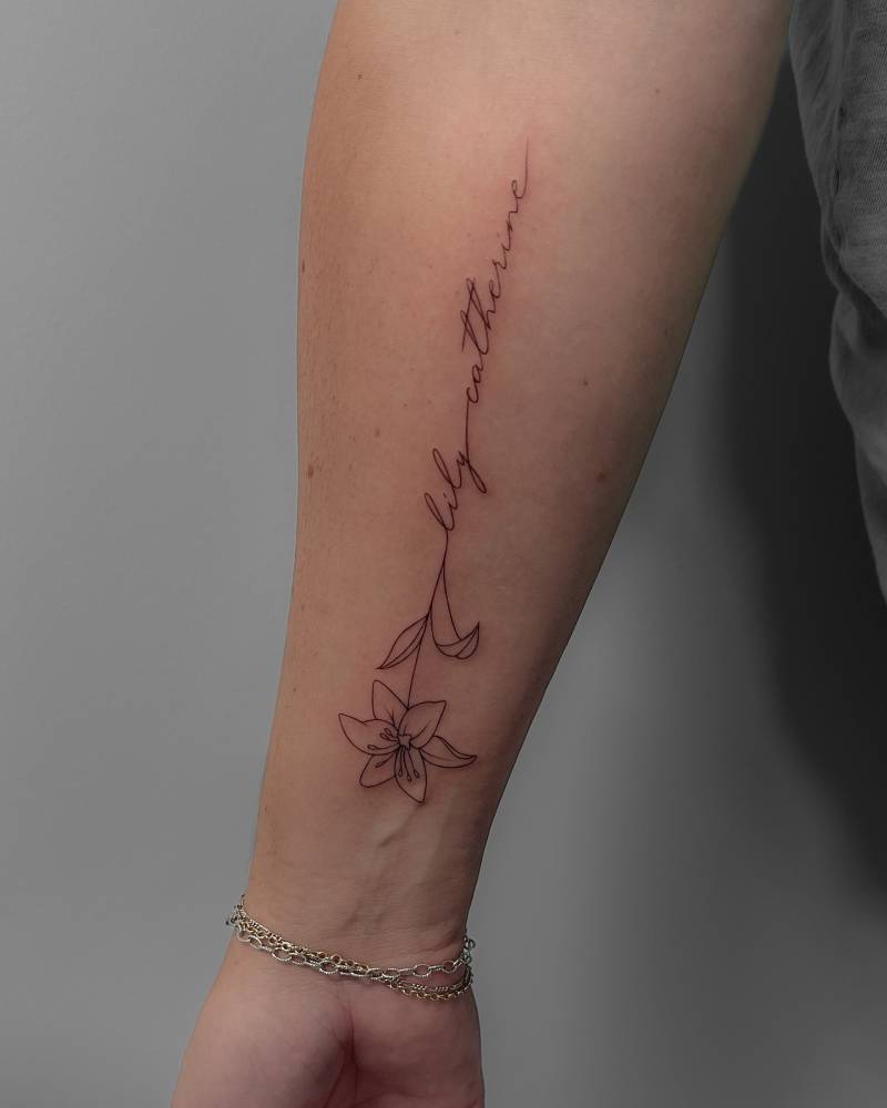 Lily flower and name "Lily Catherine" tattooed on the inner forearm.