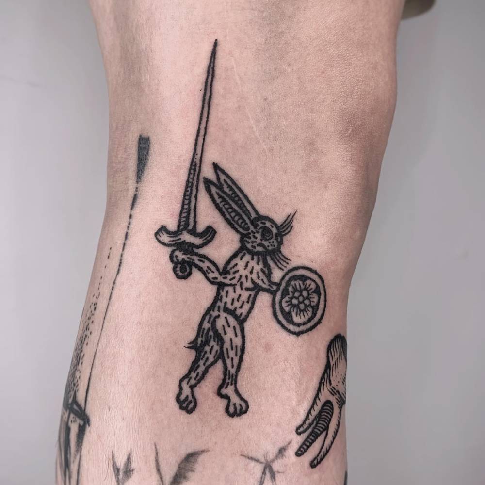 Warrior hare tattoo in engraving style located on the knee.