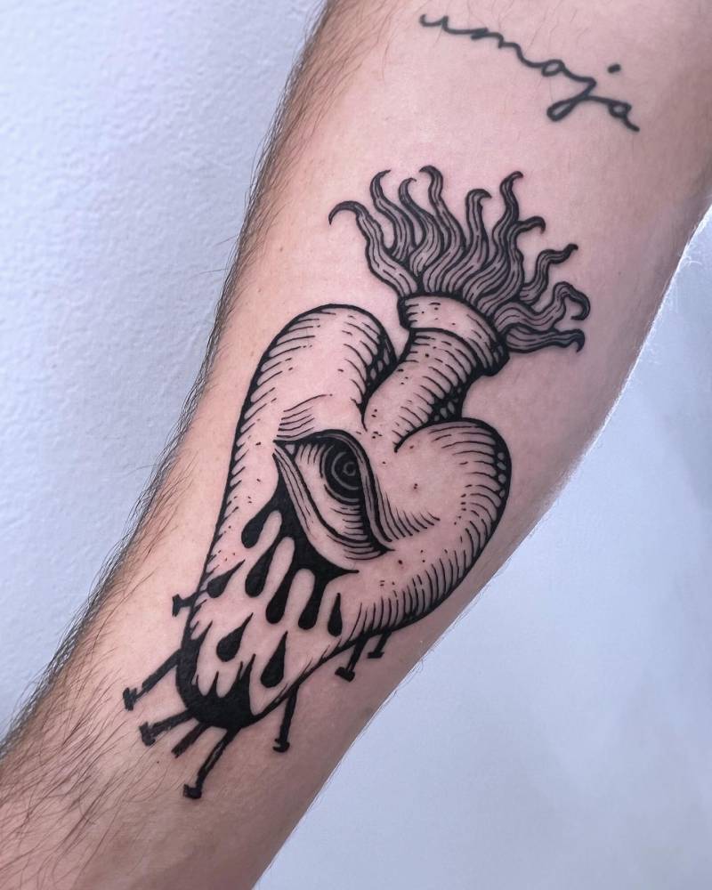 Crying flaming heart tattoo in engraving style done on the inner forearm.