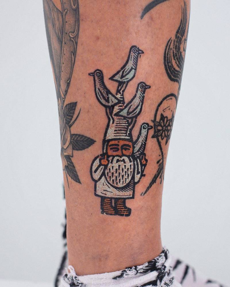 Gnome and pigeons tattoo located on the shin, pop art style.