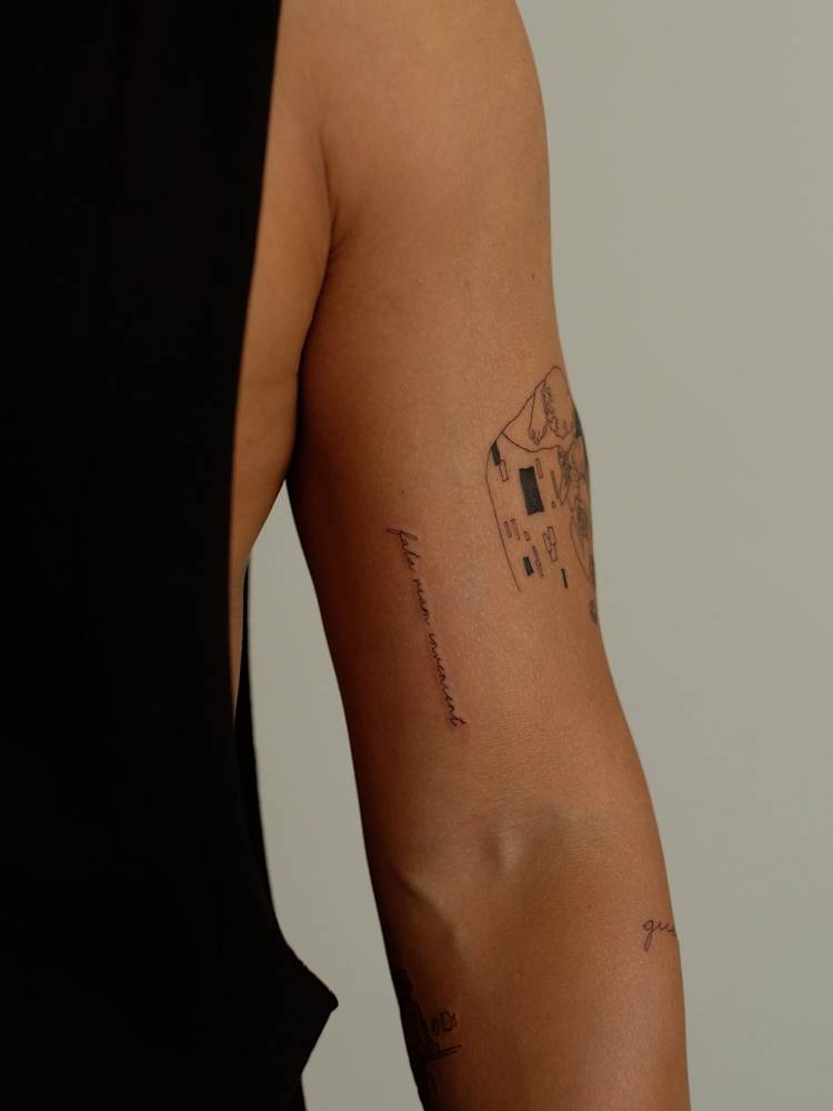 "Fata viam invenient" handwritten lettering tattoo placed on the bicep.