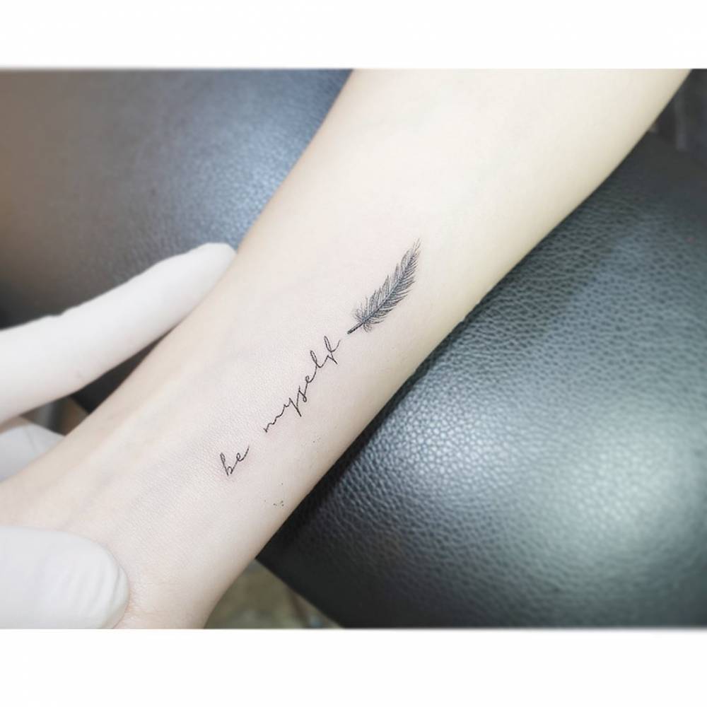 "Be myself" and feather tattoo located on the wrist.