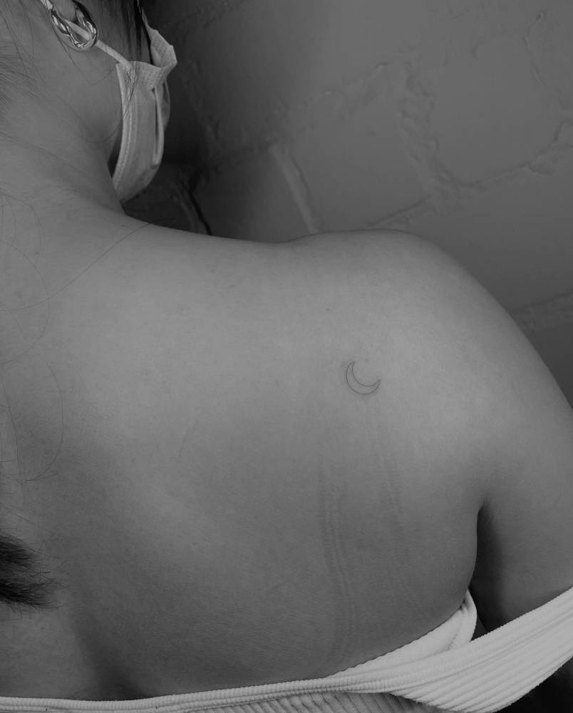 Fine line style crescent moon tattoo done on the shoulder blade.