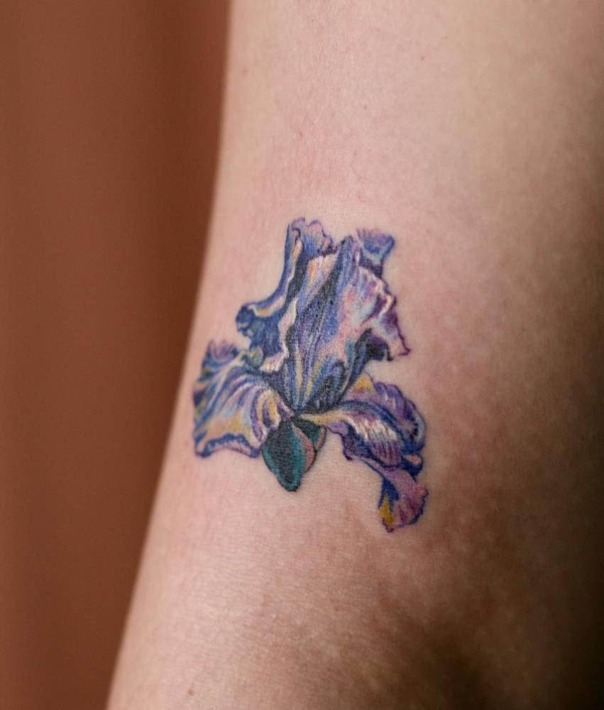 Iris flower tattoo done on the upper arm, watercolor style.