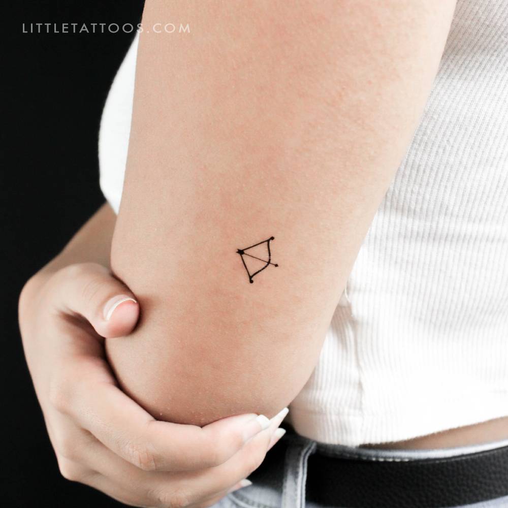 Tiny minimalist bow and arrow temporary tattoo located on the tricep.