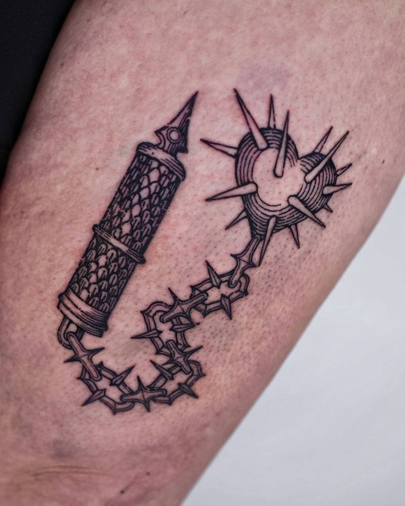 Engraving style heart shaped flail tattoo located on the thigh.