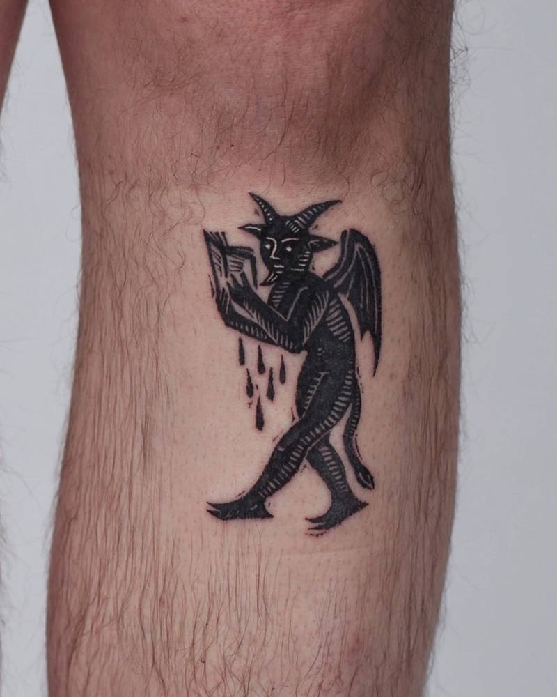 Engraving style devil tattoo located on the shin.