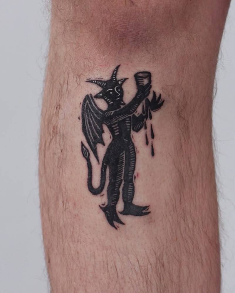 Engraving style devil tattoo located on the shin.