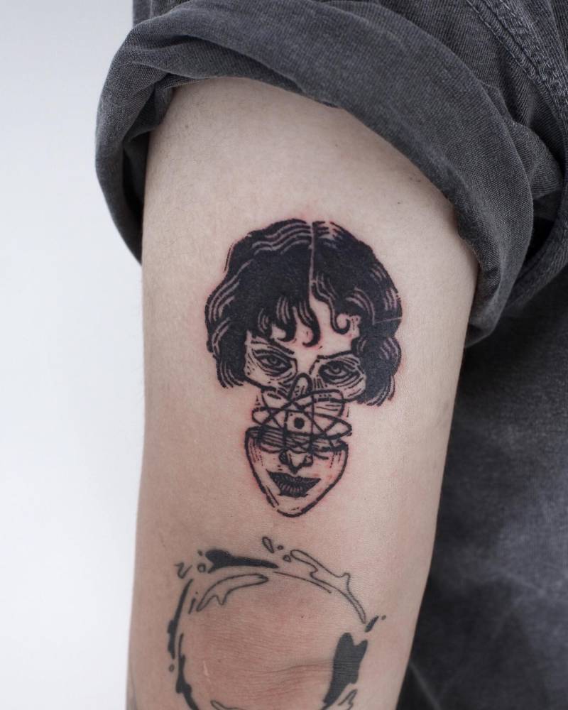 Woman head and atom tattoo located on the tricep.