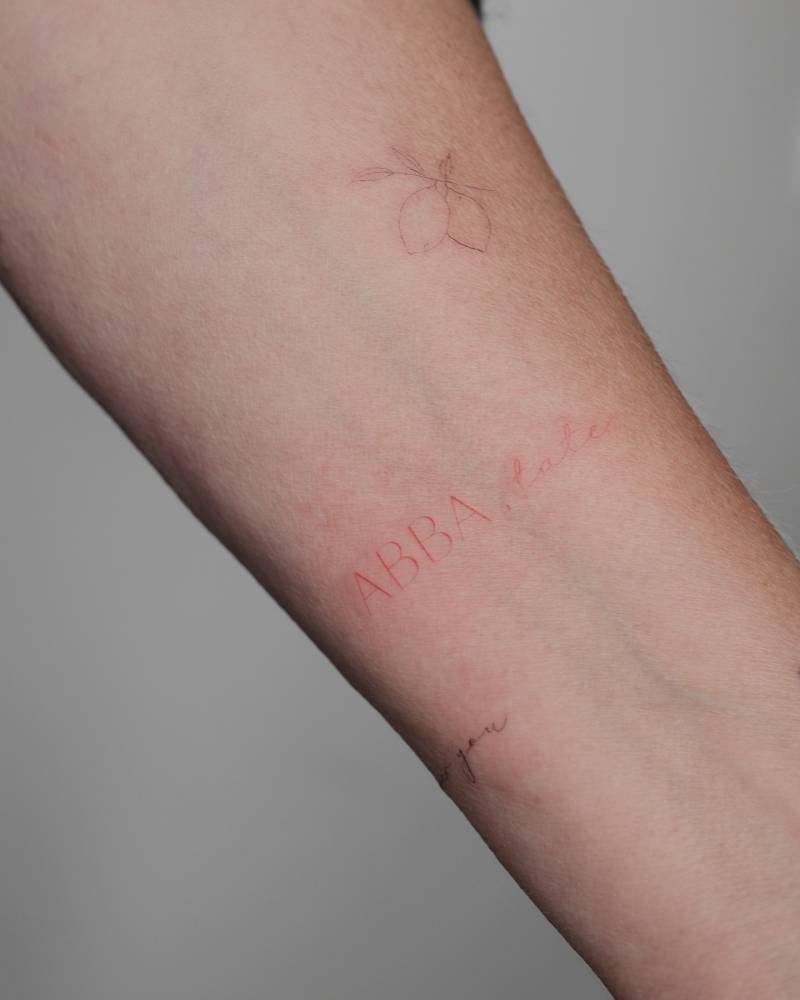 ABBA tattoo in red ink located on the inner forearm.