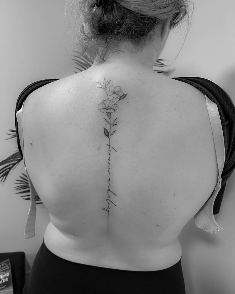 Flower bouquet and "forever and always" tattoo located on the spine.