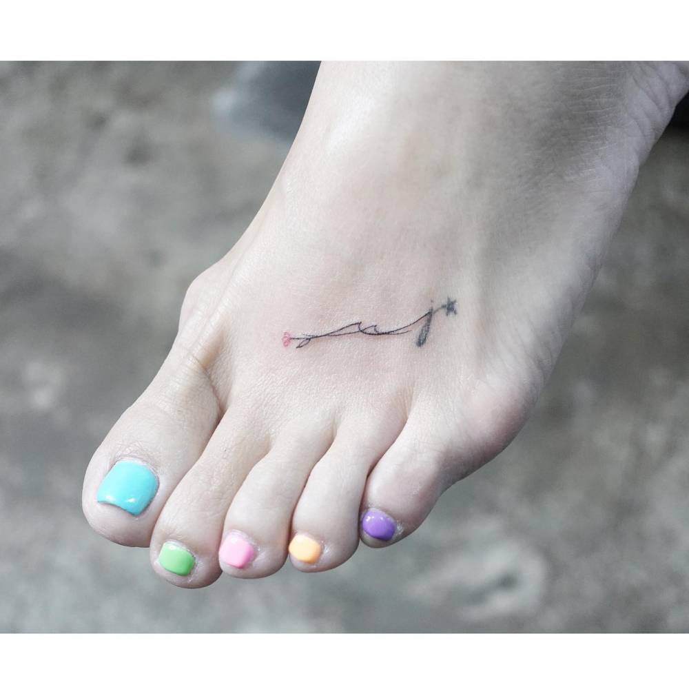 Fine line style flower and waves tattoo located on the foot.