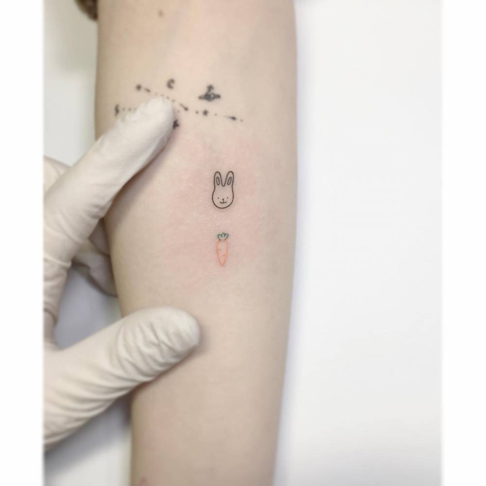 Tiny rabbit and carrot tattoos in minimalistic style placed on the inner forearm.