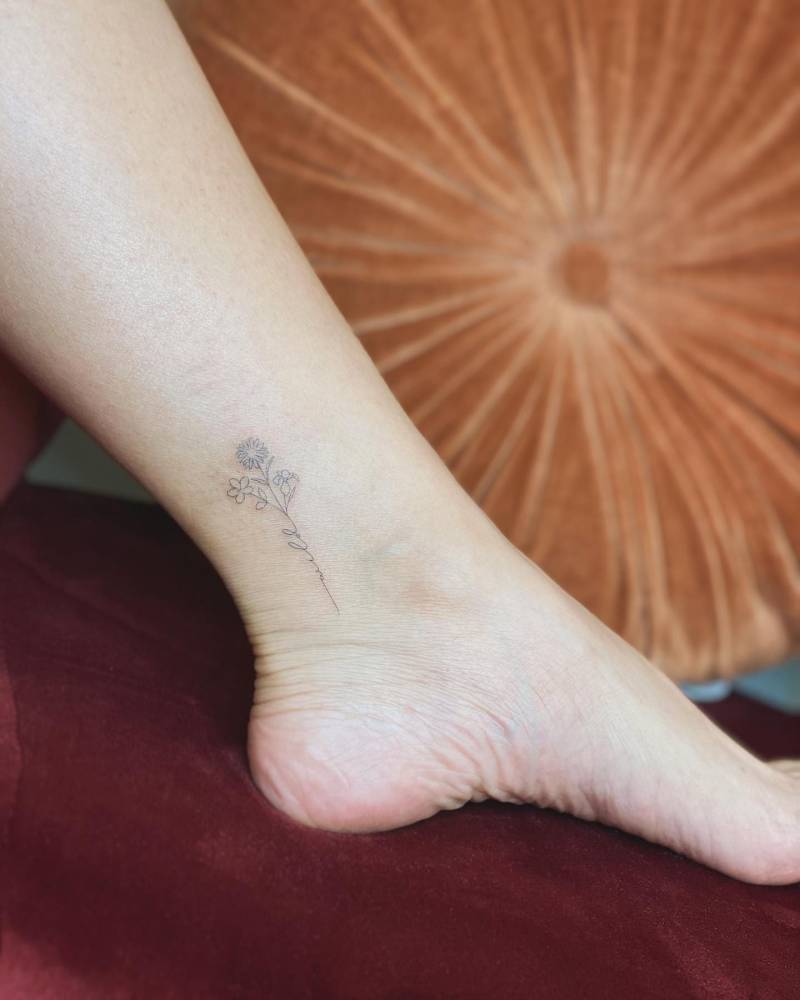 Flower bouquet tattoo in fine line style located on the ankle.