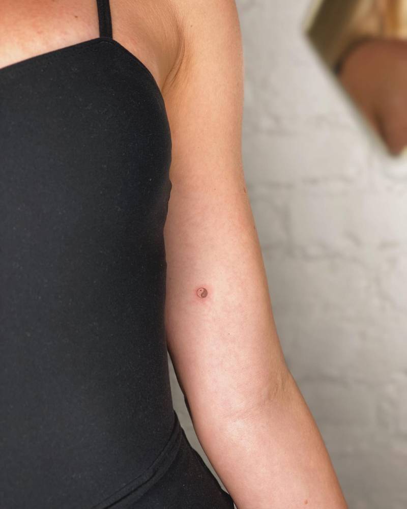Micro Yin Yang tattoo in minimalistic style located on the inner arm.