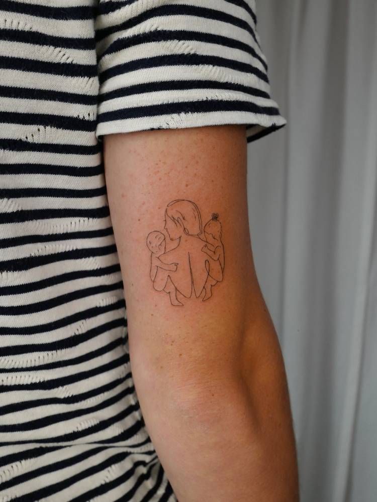 Fine line style motherhood tattoo placed on the tricep.