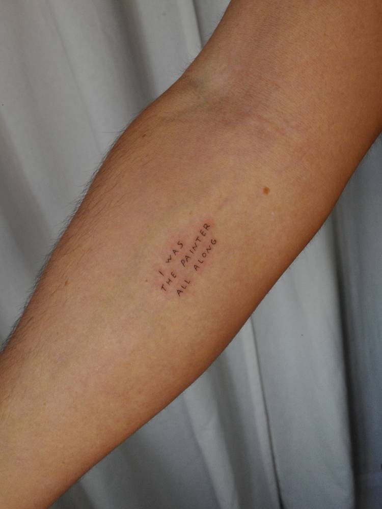 "I was the painter all along" lettering tattoo handwritten on the inner forearm.