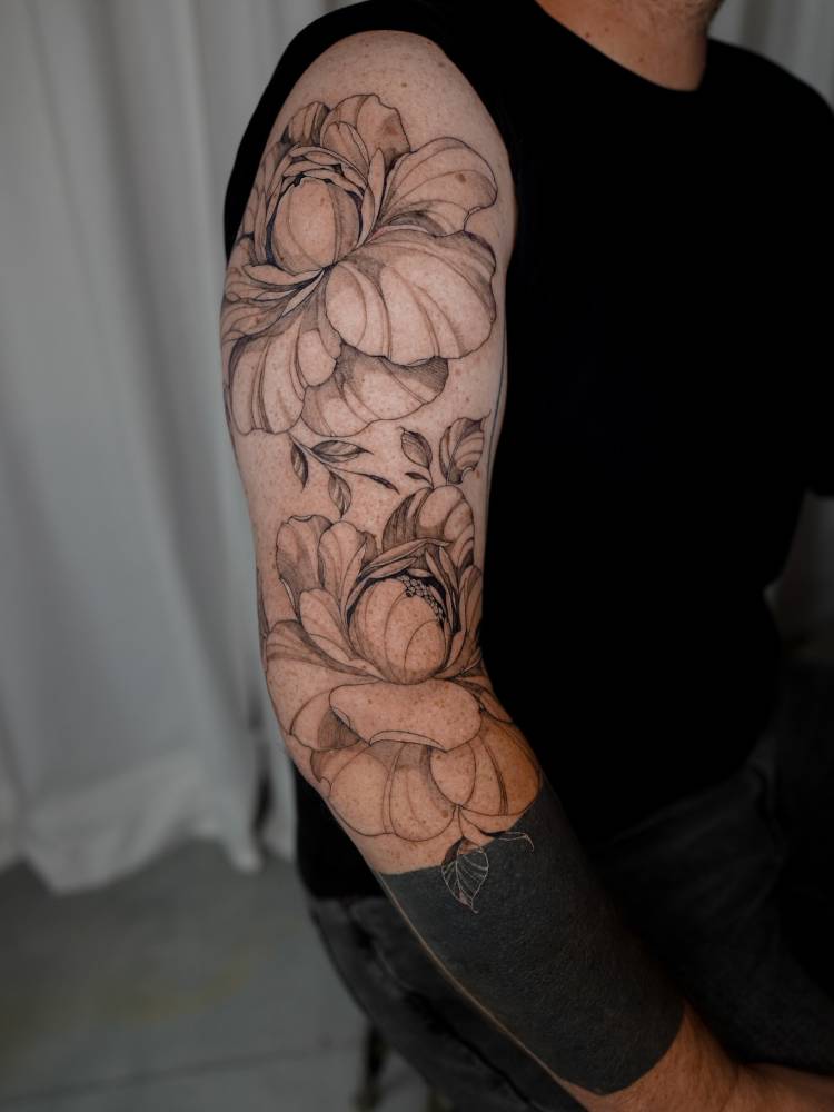 Peony flowers tattoo located on the upper arm, illustrative style.