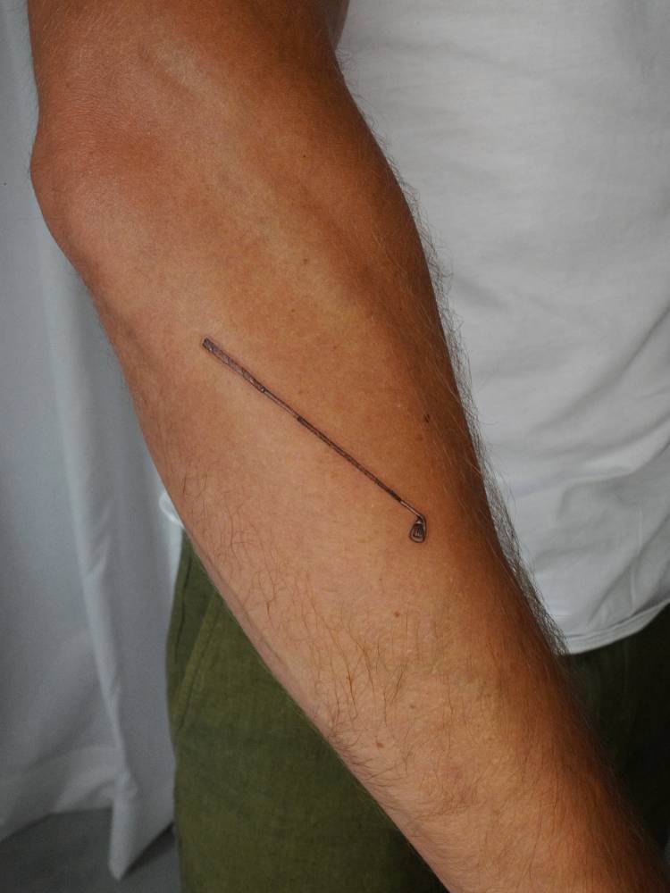 Golf club tattoo in illustrative style located on the forearm.