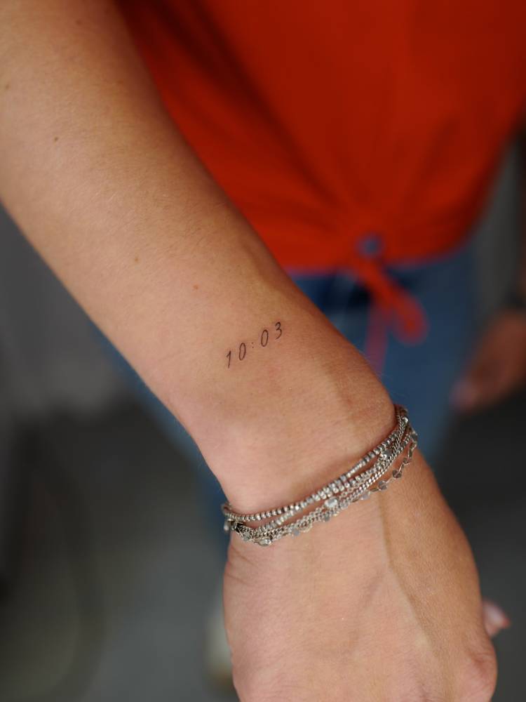 Minimalistic style hour tattoo located on the wrist.