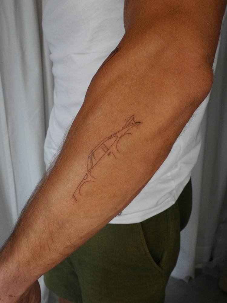 Fine line style Porsche tattoo located on the forearm.