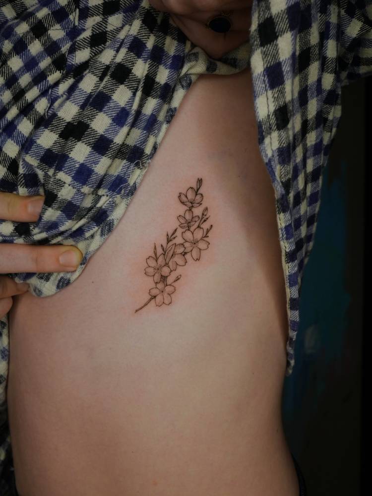 Cherry blossom tattoo in illustrative style located on the rib.