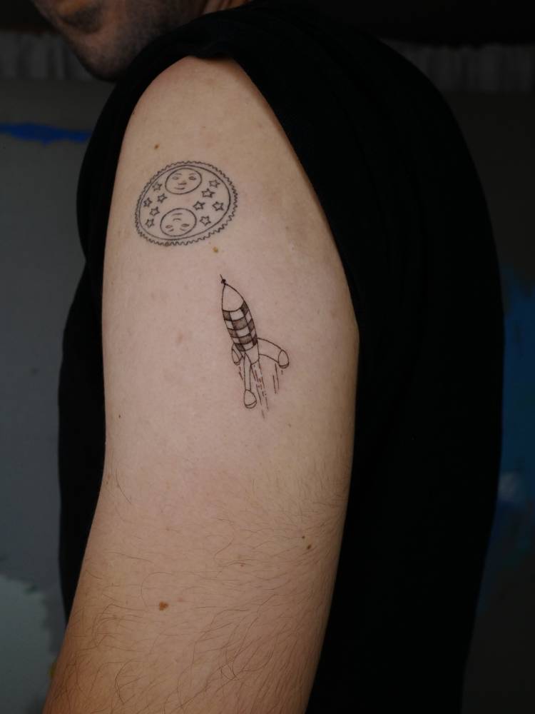 Rocket tattoo located on the upper arm, done in illustrative style.