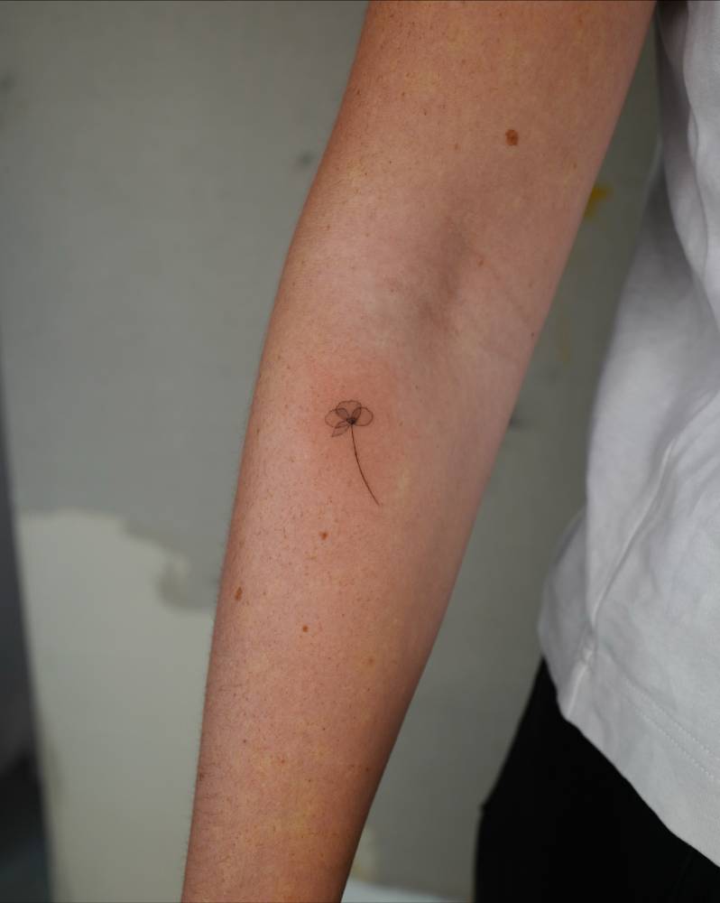 X-ray flower tattoo in illustrative style located on the inner forearm.