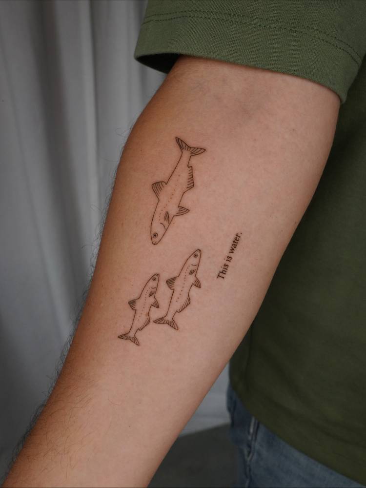 Three fish tattoo in illustrative style located on the inner forearm.