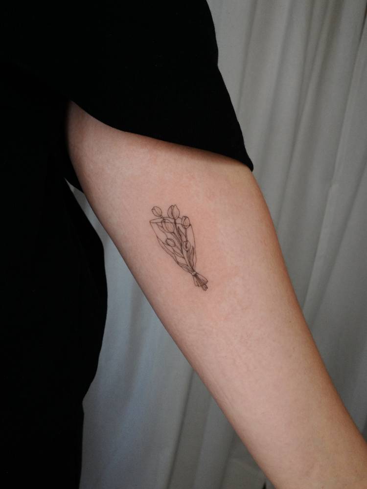 Tulip flower bouquet tattoo located on the inner forearm.