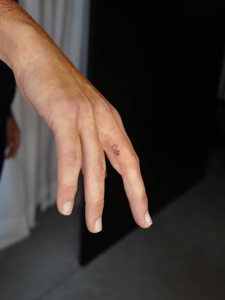 Minimalistic style Initials tattoo located on the finger.