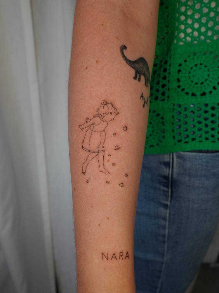 Child playing tattooed on the forearm, done in fine line style.