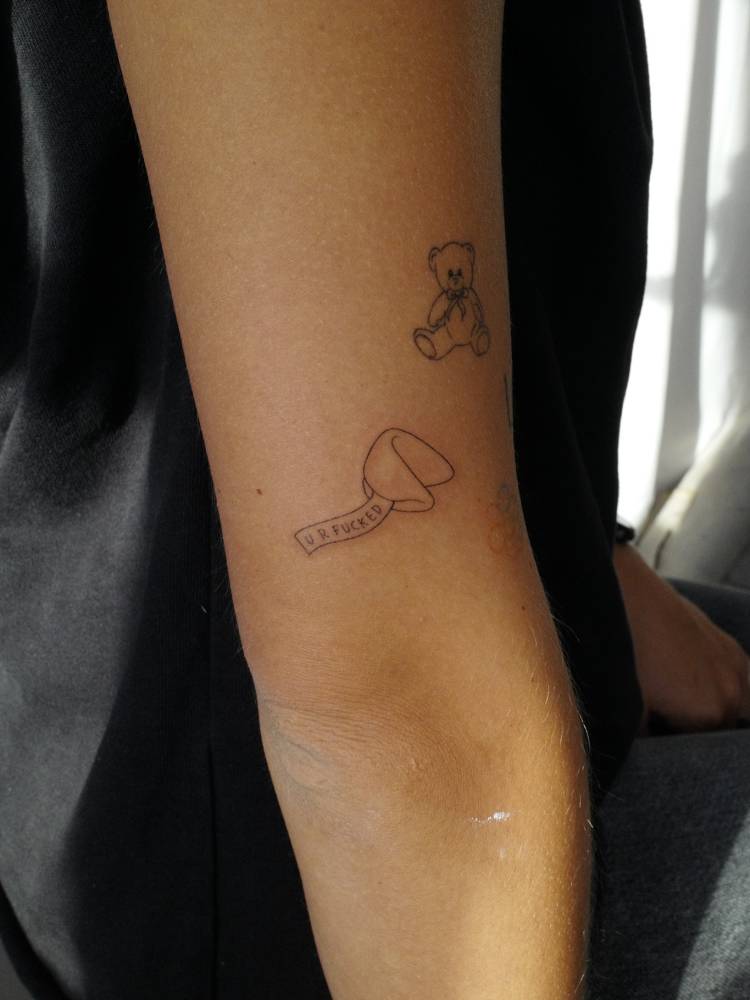 Fortune cookie tattoo in fine line style located on the upper arm.