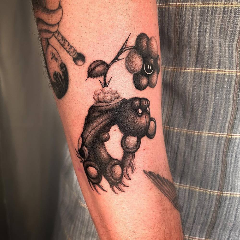 Dotwork style teddy bear and flower tattoo placed on the forearm.