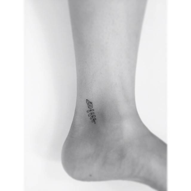 Minimalistic style flower tattoo located on the ankle.